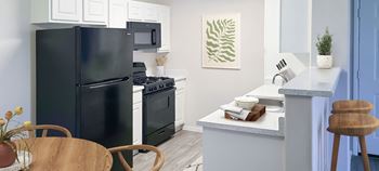 A kitchen with a black refrigerator freezer next to a stove top oven